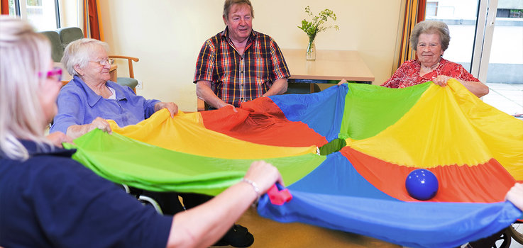 Seniorengruppe macht Übung mit Regenbogentuch